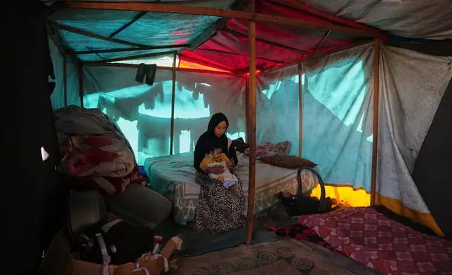 Shaimaa Wadi, 25, sits with her 1-year-old daughter Tala, inside their tent in a makeshift camp for displaced Palestinians in Deir al-Balah, central Gaza Strip, Saturday, Dec. 27, 2025. (AP Photo/Abdel Kareem Hana)