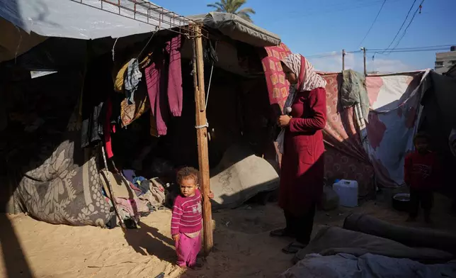 Siraj Obeid, 27, looks at her daughter as they stand in their tent in a makeshift camp for displaced Palestinians in Deir al-Balah, central Gaza Strip, Saturday, Dec. 27, 2025. (AP Photo/Abdel Kareem Hana)