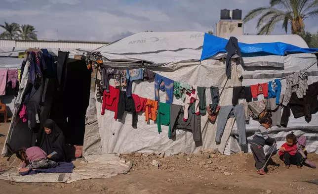 Reham Al-Helou, 35, sits at the entrance of her tent as her children play outside in a makeshift camp for displaced Palestinians in Deir al-Balah, central Gaza Strip, Saturday, Dec. 27, 2025. (AP Photo/Abdel Kareem Hana)