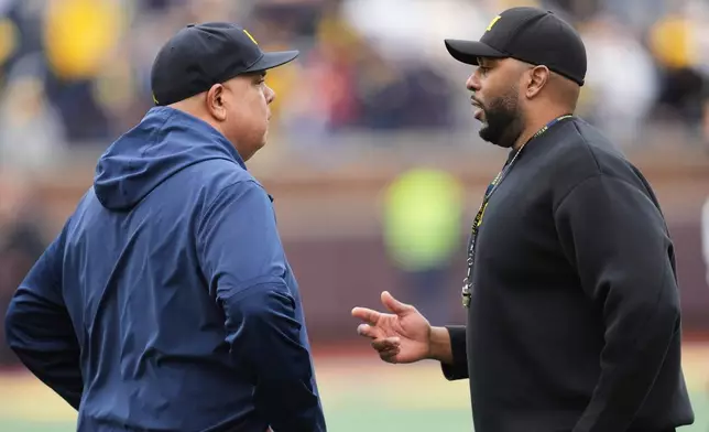 FILE - Michigan athletic director Warde Manuel, left, talks with head coach Sherrone Moore, right, before an NCAA college football spring game in Ann Arbor, Mich., April 19, 2025. (AP Photo/Paul Sancya, file)