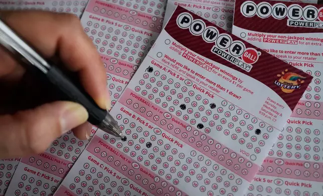 A customer fills out a Powerball lottery ticket at a convenience store in Mundelein, Ill., Monday, Dec. 15, 2025. (AP Photo/Nam Y. Huh)