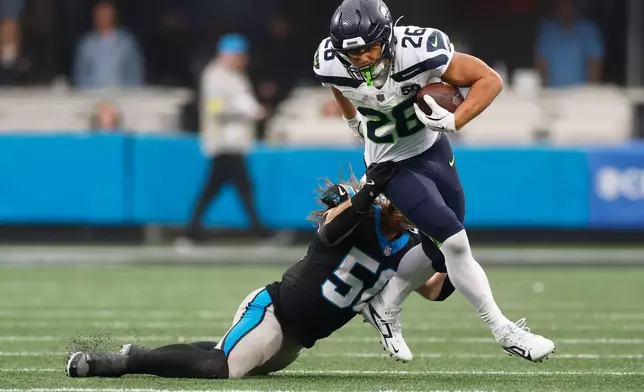 Seattle Seahawks running back Zach Charbonnet. is tackled by Carolina Panthers linebacker Christian Rozeboom during the second half of an NFL football game, Sunday, Dec. 28, 2025, in Charlotte, N.C. (AP Photo/Rusty Jones)