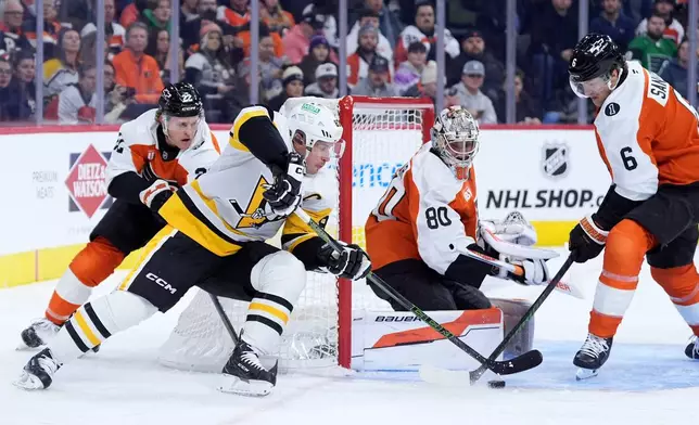 Pittsburgh Penguins' Sidney Crosby, center, tries to get a shot past Philadelphia Flyers' Travis Sanheim, from right, Dan Vladar and Christian Dvorak during the first period of an NHL hockey game Monday, Dec. 1, 2025, in Philadelphia. (AP Photo/Matt Slocum)