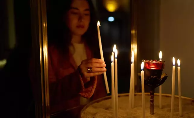 A person lights a candle during service at St. Sophia Greek Orthodox Cathedral Tuesday, Nov. 18, 2025, in Los Angeles. (AP Photo/Allison Dinner)