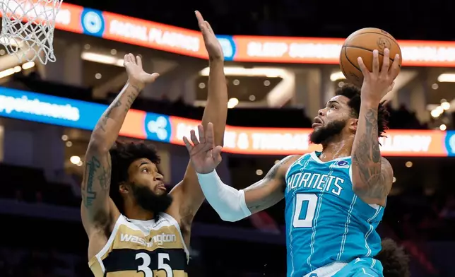 Charlotte Hornets forward Miles Bridges (0) drives to the basket against Washington Wizards forward Marvin Bagley III during the first half of an NBA basketball game in Charlotte, N.C., Tuesday, Dec. 23, 2025. (AP Photo/Nell Redmond)