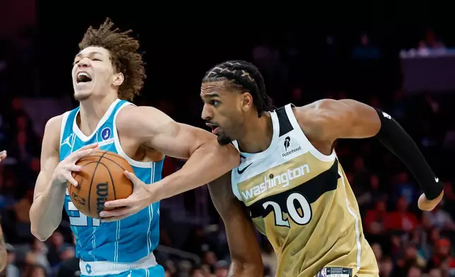 Charlotte Hornets forward Tidjane Salaun, left, drives to the basket against Washington Wizards center Alex Sarr (20) during the first half of an NBA basketball game in Charlotte, N.C., Tuesday, Dec. 23, 2025. (AP Photo/Nell Redmond)