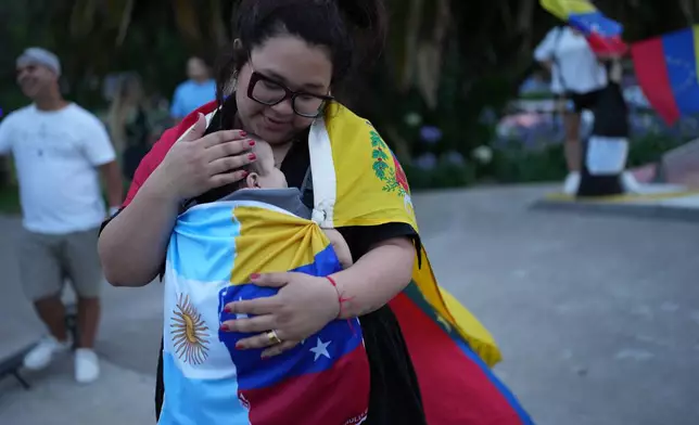 Ariana Hernandez and embraces her son Emmanuel during a demonstrate ahead of the Nobel Peace Prize ceremony where Venezuelan Maria Corina Machado is among this year's laureates, in Buenos Aires, Argentina, Saturday, Dec. 6, 2025. (AP Photo/Rodrigo Abd)