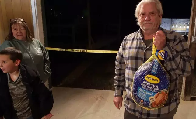 Roger Jones shows off a frozen turkey he won during a turkey shoot at Moose Lodge 1318 in Wake Forest, N.C., on Friday, Dec. 12, 2025. He drove 45 minutes to attend the shooting match. (AP Photo/Allen G. Breed)