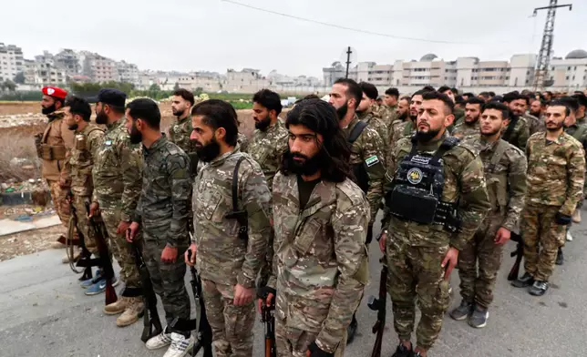 Soldiers of the new Syrian army stand in formation before a parade as part of celebrations marking the first anniversary of the ousting of the Bashar Assad regime in Douma, on the outskirts of Damascus, Syria, Monday, Dec. 8, 2025. (AP Photo/Omar Sanadiki)