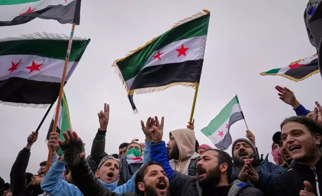 People celebrate and wave Syrian flags as they wait for a parade by the new Syrian army marking the first anniversary of the ousting of the Bashar Assad regime in Damascus, Syria, Monday, Dec. 8, 2025. (AP Photo/Hussein Malla)