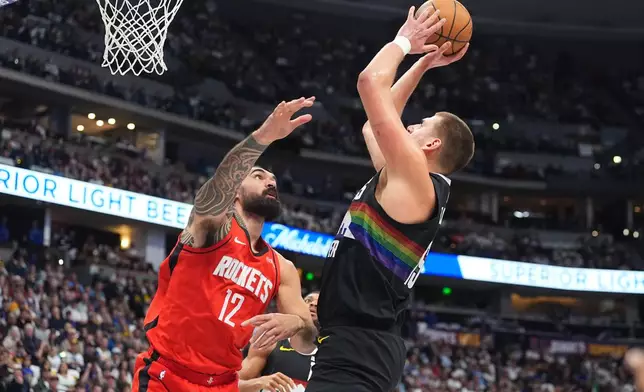 Denver Nuggets center Nikola Jokić, right, looks to shoot for a basket over Houston Rockets center Steven Adams (12) in the first half of an NBA basketball game Saturday, Dec. 20, 2025, in Denver. (AP Photo/David Zalubowski)