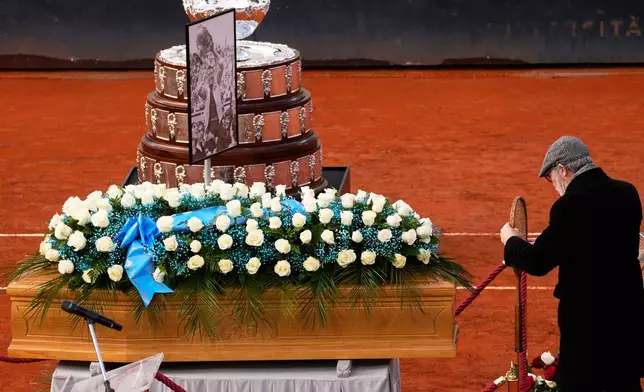 Son, Filippo Pietrangeli, lays a tennis racket as the coffin of Italian tennis champion of the 1950s and 1960s Nicola Pietrangeli is laid at the Pietrangeli tennis court at the Foro Italico ahead of the funeral service in Rome, Wednesday, Dec. 3, 2025. (AP Photo/Gregorio Borgia)