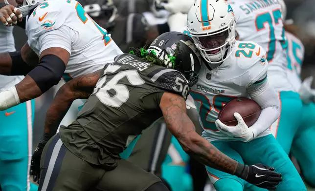 New York Jets linebacker Quincy Williams (56) hits Miami Dolphins running back De'Von Achane (28) during the second quarter of an NFL football game, Sunday, Dec. 7, 2025, in East Rutherford, N.J. (AP Photo/Yuki Iwamura)