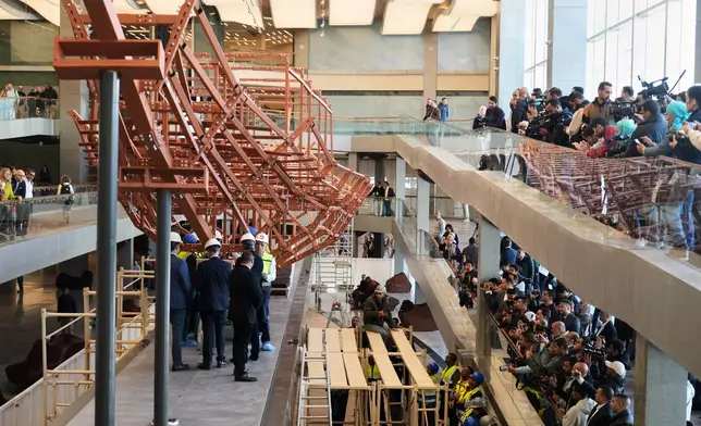 People film archeologists as they reassemble the second solar boat of King Khufu, at the Grand Egyptian Museum in Giza, Egypt, Tuesday, Dec. 23, 2025. (AP Photo/Amr Nabil)