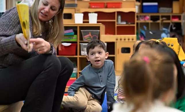 Students, including Isaac De Oliviera Matielo, center, listen as kindergarten teacher Christin Labriola, left, reads the book "Dumpling Soup" to her class, incorporating Asian American and Pacific Islander subjects in her class at Webster Hill Elementary School in West Hartford, Conn., on Dec. 2, 2025. (AP Photo/Jessica Hill)