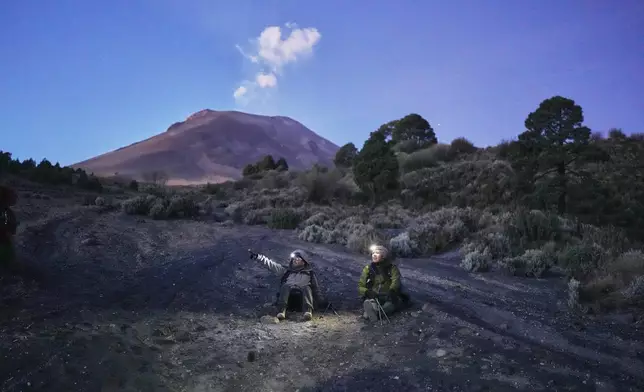 Marco Calo, left, a geophysicist at the National Autonomous University of Mexico (UNAM), take a break on the slopes of the Popocatepetl volcano in Mexico, Friday, Dec. 5, 2025. (AP Photo/Eduardo Verdugo)