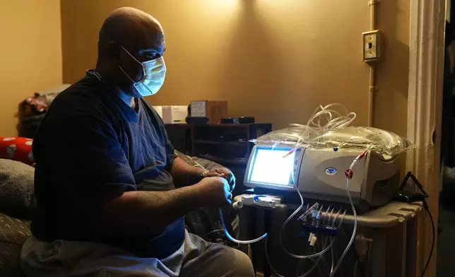 Ahmad Collins, a city government worker and former Penn State linebacker, prepares for his nightly dialysis treatment at his home in Harrisburg, Pa., Thursday, Dec. 11, 2025. (AP Photo/Matt Rourke)