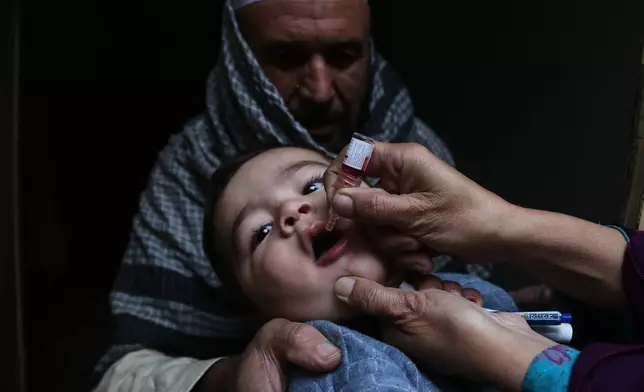 A health worker administers a polio vaccine to a child at a neighbourhood in Peshawar, Pakistan, Monday, Monday, Dec. 15, 2025. (AP Photo/Muhammad Sajjad)