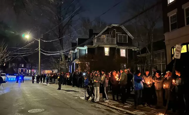 A crowd of people holding candles gather outside the home of Massachusetts Institute of Technology professor Nuno F.G. Loureiro in Brookline, Mass., Tuesday, Dec. 16, 2025. (AP Photo/Leah Willingham)