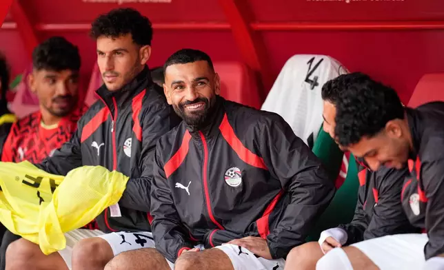 Egypt's Mohamed Salah, center, smiles as he sits on the bench ahead of the Africa Cup of Nations group B soccer match between Angola and Egypt in Agadir, Morocco, Monday, Dec. 29, 2025. (AP Photo/Mosa'ab Elshamy)