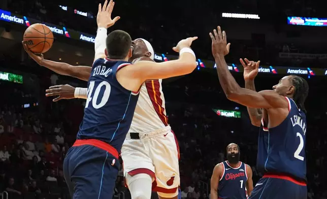 Miami Heat center Bam Adebayo, center, goes to the basket as Los Angeles Clippers center Ivica Zubac (40) and forward Kawhi Leonard (2) defend during the first half of an NBA basketball game, Monday, Dec. 1, 2025, in Miami. (AP Photo/Lynne Sladky)