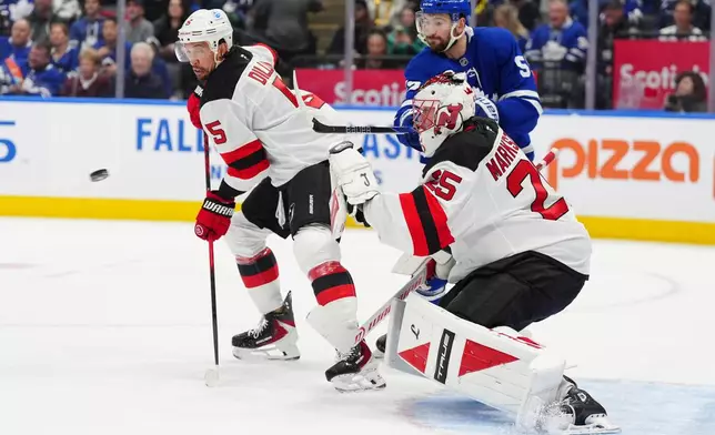 New Jersey Devils goaltender Jacob Markstrom (25) watches the puck as Devils defenseman Brenden Dillon (5) and Toronto Maple Leafs center Nicolas Roy (55) battle in front during second period NHL hockey action in Toronto on Tuesday Dec. 30, 2025. (Frank Gunn/The Canadian Press via AP)