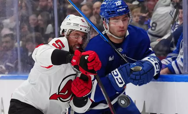 Toronto Maple Leafs' Jacob Quillan and New Jersey Devils defenceman Brenden Dillon (5) battle along the boards for the puck during the second period of an NHL hockey game in Toronto, Tuesday Dec. 30, 2025. (Frank Gunn/The Canadian Press via AP)