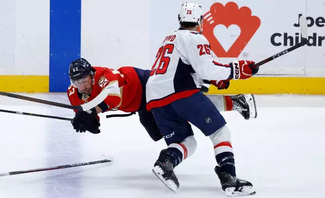 Washington Capitals center Nic Dowd (26) watches Florida Panthers left wing Brad Marchand (63) who wastripped by right wing Ryan Leonard during the second period of an NHL hockey game, Monday, Dec. 29, 2025, in Sunrise, Fla. (AP Photo/Rhona Wise)