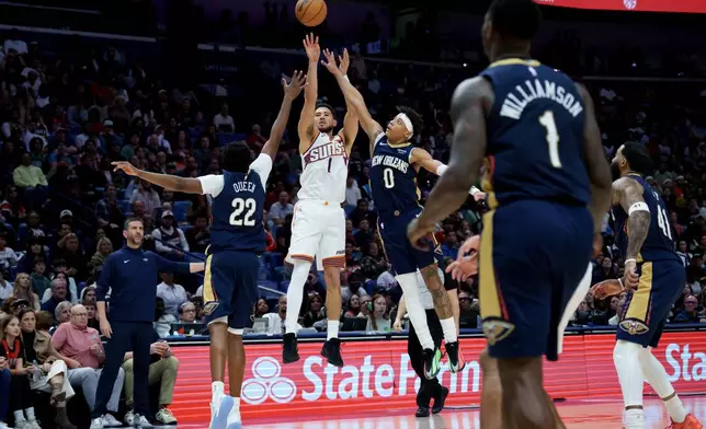 Phoenix Suns guard Devin Booker (1) shoots against New Orleans Pelicans center Derik Queen (22) and guard Jeremiah Fears (0) during the second half of an NBA basketball game in New Orleans, Saturday, Dec. 27, 2025. (AP Photo/Matthew Hinton)