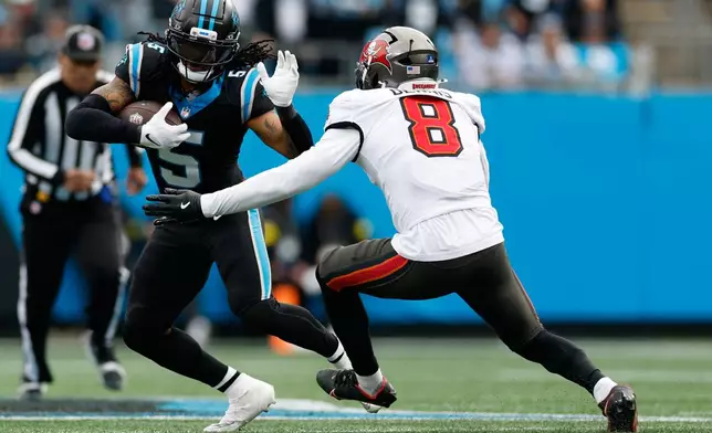 Carolina Panthers running back Rico Dowdle runs past Tampa Bay Buccaneers linebacker Sirvocea Dennis during the first half of an NFL football game, Sunday, Dec. 21, 2025, in Charlotte, N.C. (AP Photo/Rusty Jones)