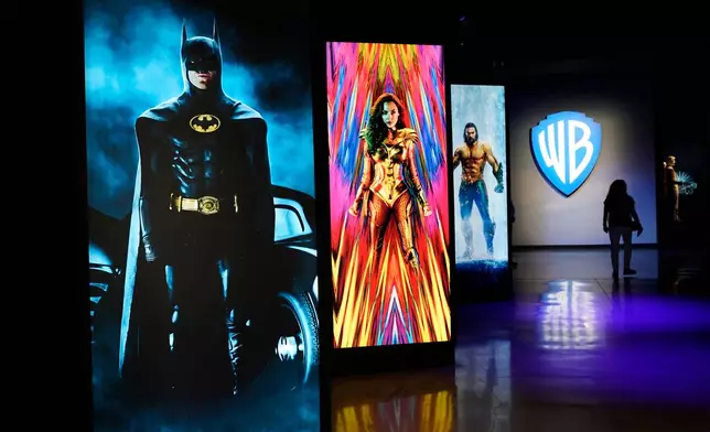 FILE - A visitor walks past portraits of DC Comics superheroes as she enters the "Action and Magic Made Here" interactive experience at the Warner Bros. Studio Tour Hollywood media preview on June 24, 2021, in Burbank, Calif. (AP Photo/Chris Pizzello, File)