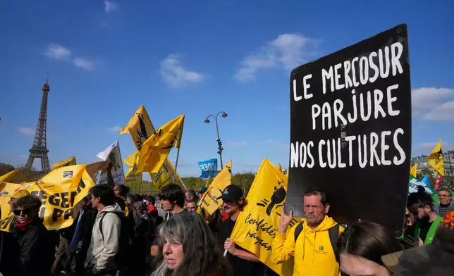 FILE - French farmers protest with a poster reading "Mercosur betrays our cultures" against the Mercosur trade alliance with South America countries Tuesday, Oct. 14, 2025 near the Eiffel Tower in Paris. (AP Photo/Michel Euler, File)