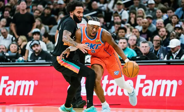 Oklahoma Thunder guard Shai Gilgeous-Alexander (2) dribbles against San Antonio Spurs forward Keldon Johnson (3) during the first half of an NBA basketball game in San Antonio, Tuesday, Dec. 23, 2025. (AP Photo/Rodolfo Gonzalez)