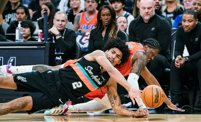 San Antonio Spurs guard Dylan Harper (2) and Oklahoma Thunder guard Jalen Williams (8) scramble for a loose ball during the first half of an NBA basketball game in San Antonio, Tuesday, Dec. 23, 2025. (AP Photo/Rodolfo Gonzalez)