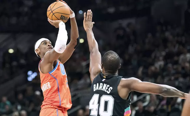 Oklahoma Thunder guard Shai Gilgeous-Alexander (2) shoots over the reach of San Antonio Spurs forward Harrison Barnes (40) during the first half of an NBA basketball game in San Antonio, Tuesday, Dec. 23, 2025. (AP Photo/Rodolfo Gonzalez)
