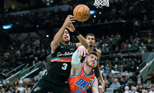 San Antonio Spurs forward Keldon Johnson (3) and Oklahoma Thunder center Isaiah Hartenstein (55) vie for a rebound during the first half of an NBA basketball game in San Antonio, Tuesday, Dec. 23, 2025. (AP Photo/Rodolfo Gonzalez)