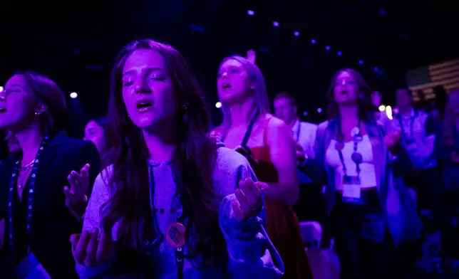 Attendees sing and pray during Faith Night worship events at Turning Point USA's AmericaFest 2025, Saturday, Dec. 20, 2025, in Phoenix. (AP Photo/Jon Cherry)