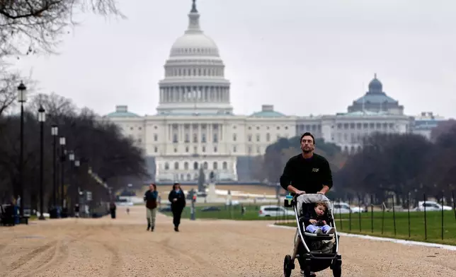 A visitor and his son walk along the National Mall near the Capitol, Wednesday, Nov. 26, 2025, in Washington. (AP Photo/Rahmat Gul)