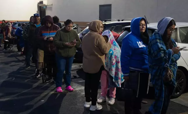 People wait in line to buy masa, a dough used to make tamales, outside Amapola Market in Downey, Calif., early Tuesday morning, Dec. 23, 2025. (AP Photo/Jae C. Hong)