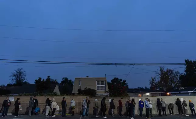 People wait in line to buy masa, a dough used to make tamales, outside Amapola Market in Downey, Calif., early Tuesday morning, Dec. 23, 2025. (AP Photo/Jae C. Hong)