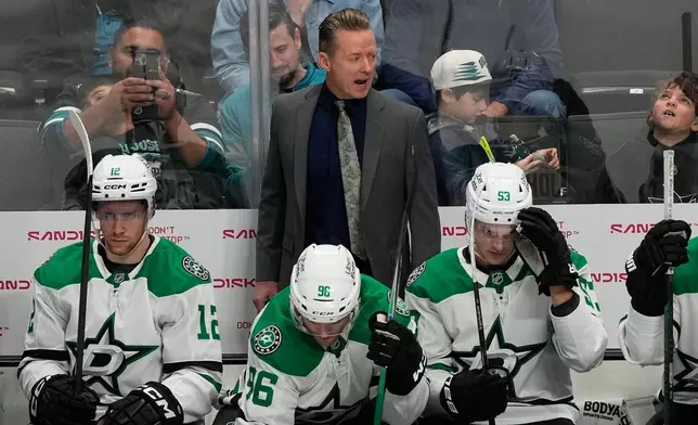 Dallas Stars head coach Glen Gulutzan, standing, reacts behind players during the third period of an NHL hockey game against the San Jose Sharks in San Jose, Calif., Thursday, Dec. 18, 2025. (AP Photo/Jeff Chiu)