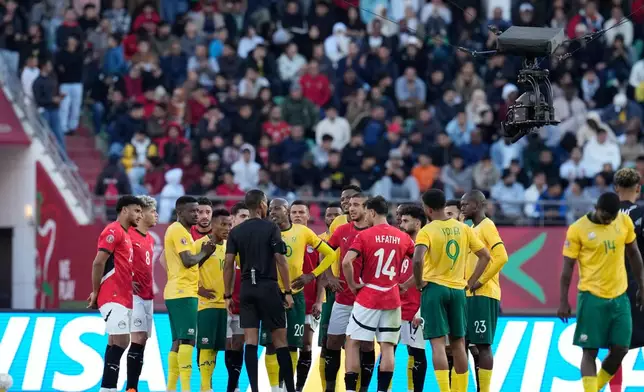 Players gather around the referee Pacifique Ndabihawenimana while a penalty kick check is being conducted during the Africa Cup of Nations group B soccer match between Egypt and South Africa in Agadir, Morocco, Friday, Dec. 26, 2025. (AP Photo/Themba Hadebe)