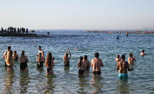 Surfers and swimmers head out to the ocean as a tribute following Sunday's shooting at Bondi Beach, in Sydney, Friday, Dec. 19, 2025. (AP Photo/Steve Markham)