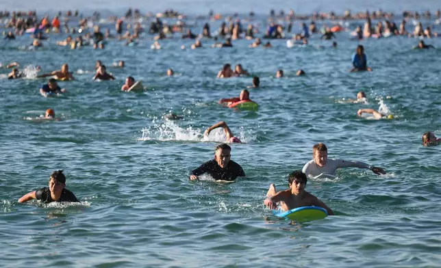 FILE - Surfers and swimmers head out to the ocean as a tribute following Sunday's shooting at Bondi Beach, in Sydney, Friday, Dec. 19, 2025. (AP Photo/Steve Markham,File)
