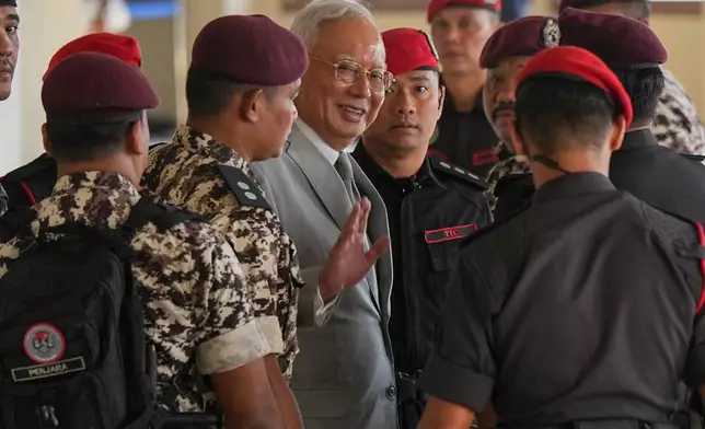 Former Malaysian Prime Minister Najib Razak, center, is escorted by prison officers on his arrival at the Kuala Lumpur High Court Complex, in Kuala Lumpur, Malaysia, Monday, Dec. 22, 2025. (AP Photo/Azneal Ishak)