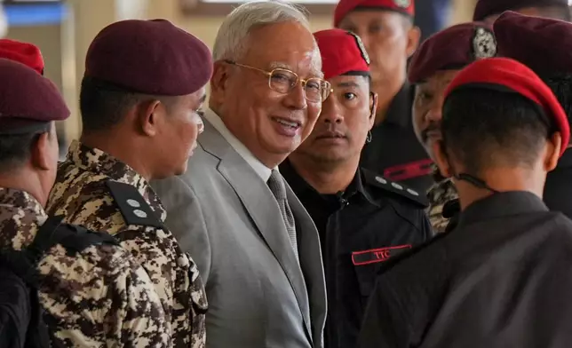 Former Malaysian Prime Minister Najib Razak, center, is escorted by prison officers on his arrival at the Kuala Lumpur High Court Complex, in Kuala Lumpur, Malaysia, Monday, Dec. 22, 2025. (AP Photo/Azneal Ishak)