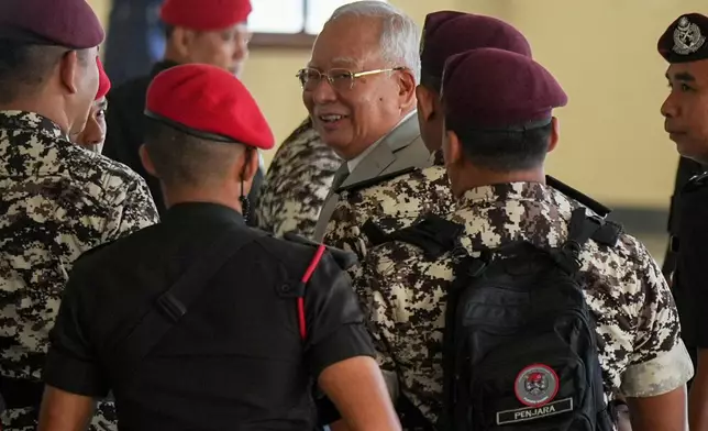 Former Malaysian Prime Minister Najib Razak, center, is escorted by prison officers on his arrival at the Kuala Lumpur High Court Complex, in Kuala Lumpur, Malaysia, Monday, Dec. 22, 2025. (AP Photo/Azneal Ishak)