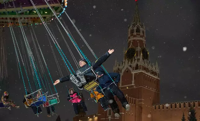 FILE - Children ride a carousel at the Christmas fair decorated for Christmas and the New Year festivities in Red Square in Moscow, Thursday, Dec. 25, 2025, with the Spasskaya Tower in the background. (AP Photo/Alexander Zemlianichenko, File)