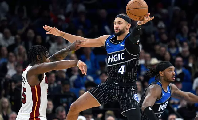 Orlando Magic guard Jalen Suggs (4) deflects a pass by Miami Heat guard Davion Mitchell, left, during the second half of an NBA Cup basketball game, Tuesday, Dec. 9, 2025, in Orlando, Fla. (AP Photo/Phelan M. Ebenhack)