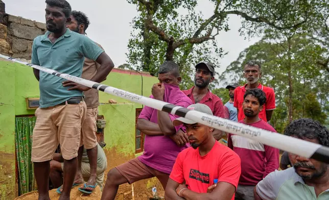 Family members and relatives of tea plantation workers watch rescuers try to dig out a buried body after a landslide following Cyclone Ditwah at Craighead Estate in Nawalapitiya, Sri Lanka, Thursday, Dec, 11, 2025. (AP Photo/Eranga Jayawardena)